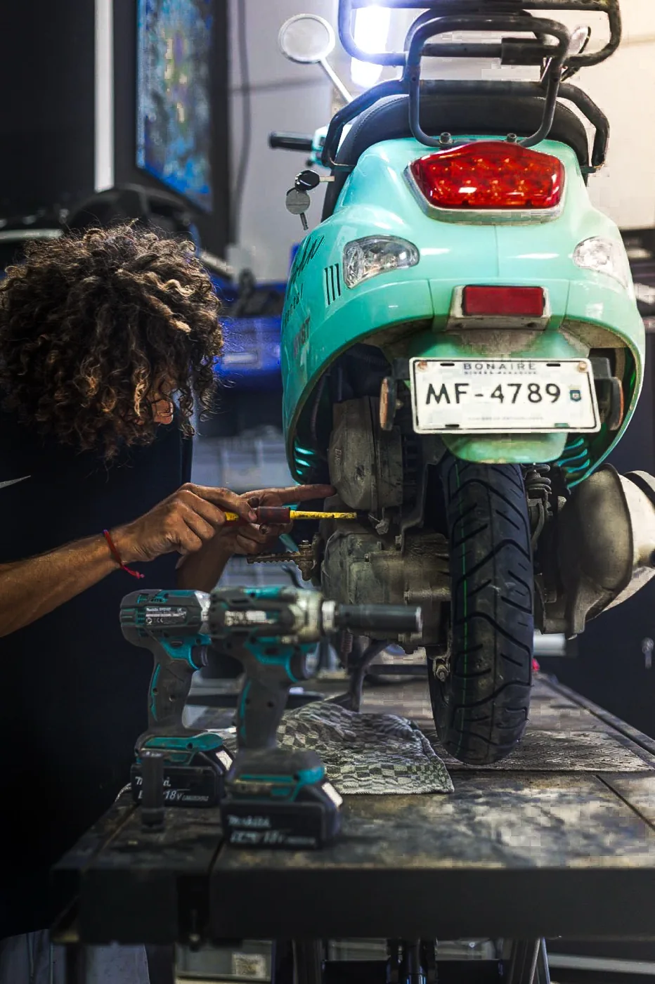 Mechanic diagnosing a scooter on the workbench, tools at the ready