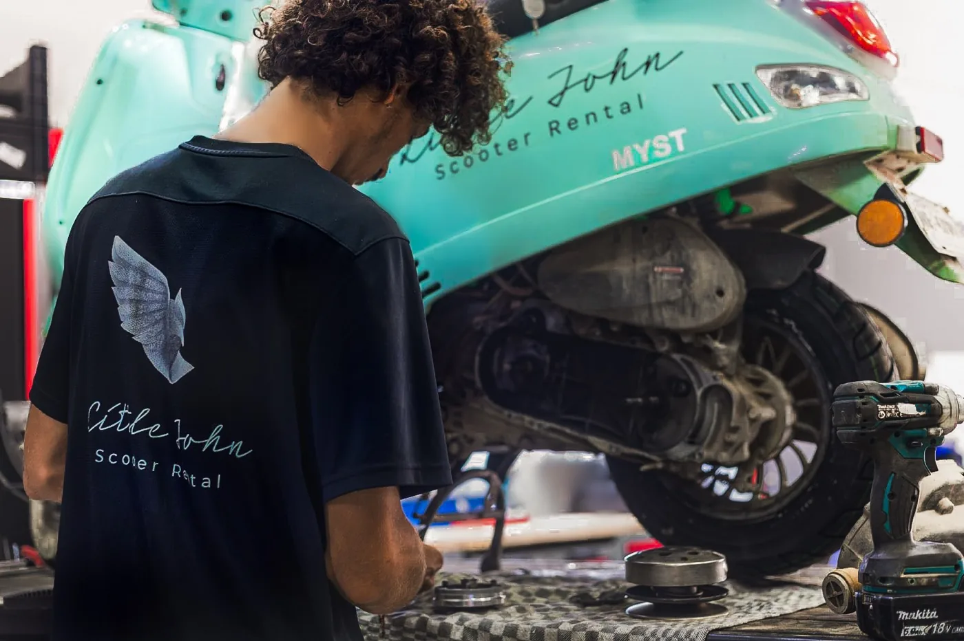 Little John mechanic in the eagle shirt working on a Myst scooter